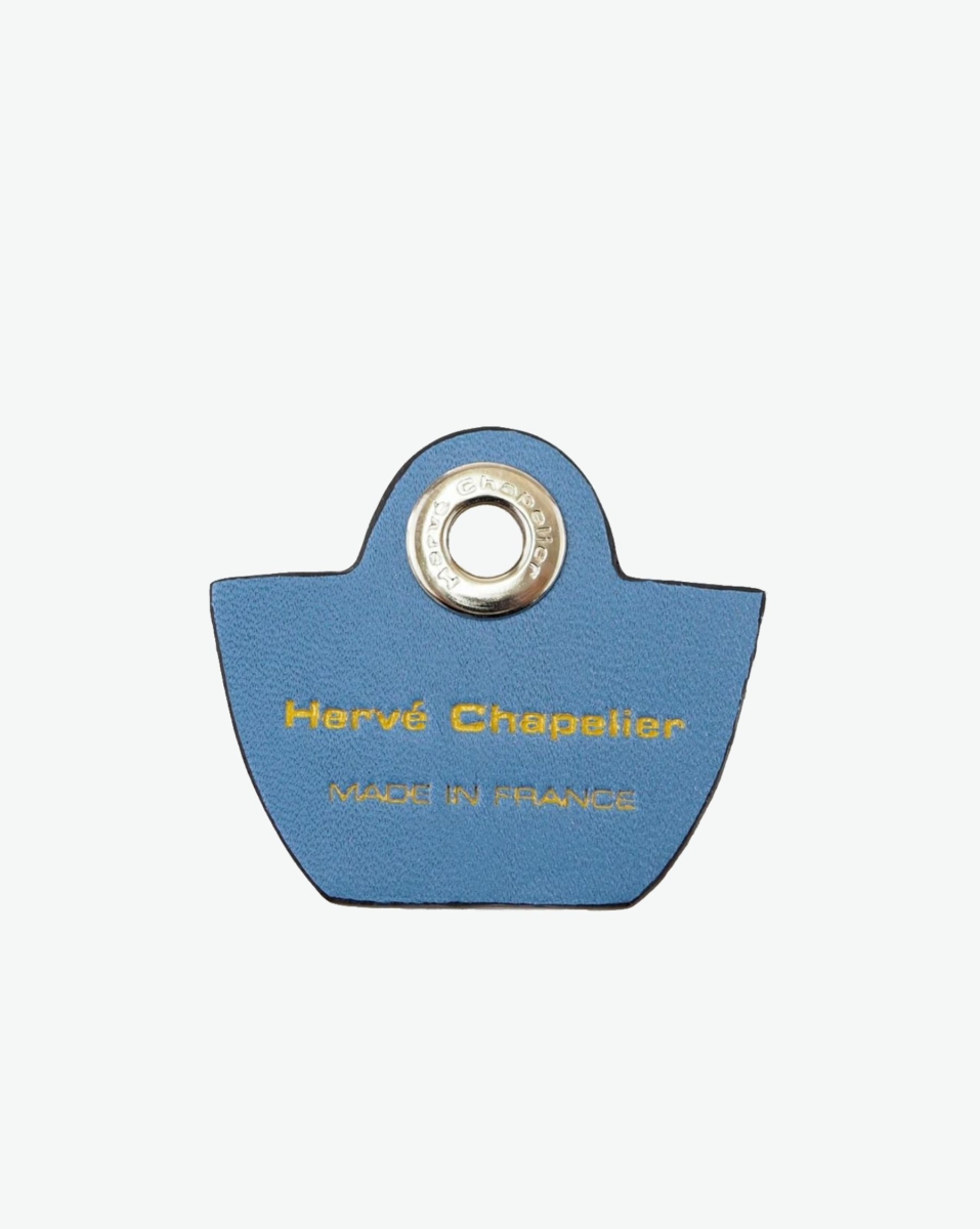 Hervé Chapelier -  - "Packshot of a 118L flat charm
in the shape of a bag with the Hervé Chapelier logo.
The charm is made of leather with a eyelet in the middle in a XXS size.
Charme en forme de sac en cuir dans une taille XXS"